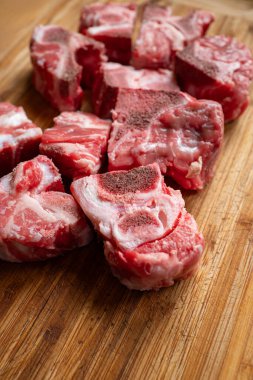 Çiğ, kesilmiş, taze sığır kuyruğu parçaları çorba çorbası veya güveç için kullanılır. Yukarıdan aşağıya, ahşap mutfak tahtasına kurulmuş, yakın çekim, insan yok.