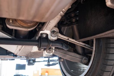 Kontrol kolu, bobin yayı, şok emici ve dengeleyici çubuğu olan araba arka dingil montajı. Geniş açı, kaldırılmış bir arabanın çekimleri, hiç insan yok.