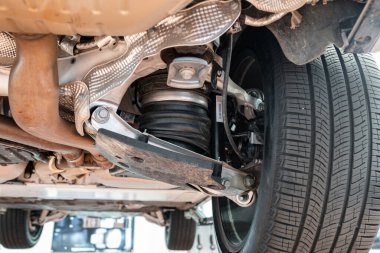 Kontrol kollu araba arka dingil montajı, lastik çizmeli hava süspansiyon amortisörü. Geniş açı, kaldırılmış bir arabanın çekimleri, hiç insan yok.