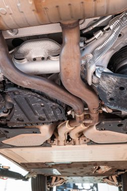 Egzoz sistemi, tekerlekleri ve dingil parçaları olan bir araba şasisi. Geniş açı, manzaralı, asansörlü araç, tamirhanenin içinde insan yok.