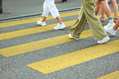 Sarı zebra ya da yaya geçidinde kesişen insanların tanınamaz haldeki bacakları. İnsanların belden aşağı görüntüsü, asfalt üzerinde bacaklar ve ayaklar, güneşli yaz günü