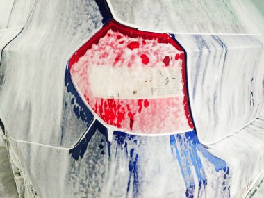 Oto yıkamada köpükle kaplanmış mavi araba, detaylı çekim, geniş açı, insan yok.