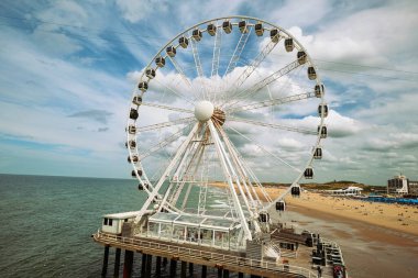 Lahey, Hollanda, 27 Ağustos 2025. Pier SkyView deniz kenarındaki dönme dolap. Geniş açı manzaralı, mavi yaz gökyüzü bulutlu, iskeleden görülüyor.