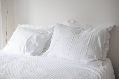 Düzenli, temiz, çarşaflı ve iki kabarık yastıklı bir yatak. Genel manzara, yatak odası, insan yok.