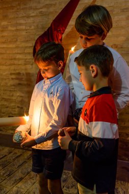 Arahal. Seville. Spain. 14th April, 2022. Children ask a penitent for wax to make a ball of wax. Penitential procession of the Brotherhood of La Misericordia on Maundy Thursday.