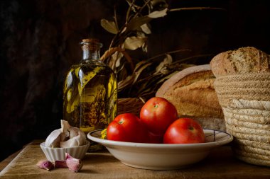 Classic still life with extra virgin olive oil, tomatoes, garlic and bread. Ingredients of a typical breakfast of the Mediterranean diet.