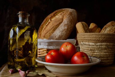 Classic still life with extra virgin olive oil, tomatoes, garlic and bread. Ingredients of a typical breakfast of the Mediterranean diet.