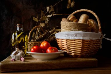Classic still life with extra virgin olive oil, tomatoes, garlic and bread. Ingredients of a typical breakfast of the Mediterranean diet.