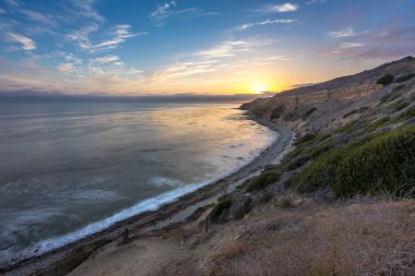 Sakin günbatımının engebeli uçurumları ve okyanus yollarının görkemli kıyı manzarasını aydınlattığı Catalina Patikası boyunca huzurlu bir yolculuğa çıkın, Rancho Palos Verdes, Kaliforniya.