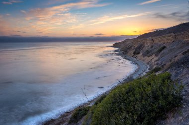Sakin günbatımının engebeli uçurumları ve okyanus yollarının görkemli kıyı manzarasını aydınlattığı Catalina Patikası boyunca huzurlu bir yolculuğa çıkın, Rancho Palos Verdes, Kaliforniya.