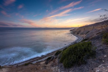 Sakin günbatımının engebeli uçurumları ve okyanus yollarının görkemli kıyı manzarasını aydınlattığı Catalina Patikası boyunca huzurlu bir yolculuğa çıkın, Rancho Palos Verdes, Kaliforniya.