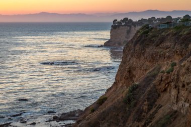 Güneş, Golden Cove 'un üzerinde batarken sakin suları, gökyüzünün ılık renklerini yansıtıyor. Rancho Palos Verdes, Kaliforniya' nın engebeli uçurumlarının arasında huzurlu bir kaçış sunuyor..