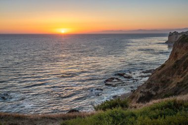 Güneş, Golden Cove 'un üzerinde batarken sakin suları, gökyüzünün ılık renklerini yansıtıyor. Rancho Palos Verdes, Kaliforniya' nın engebeli uçurumlarının arasında huzurlu bir kaçış sunuyor..