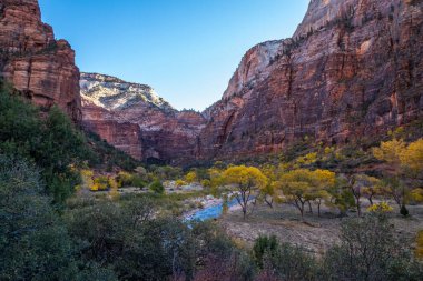 Kum tepeleri, Utah 'ta gün batımının ılık ışığını yakalıyor. Yürüyüşçüleri, Zion Ulusal Parkı' nın manzaralı manzaralarını keşfetmeye davet ediyor..