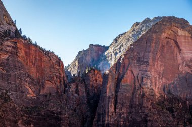 Kum tepeleri, Utah 'ta gün batımının ılık ışığını yakalıyor. Yürüyüşçüleri, Zion Ulusal Parkı' nın manzaralı manzaralarını keşfetmeye davet ediyor..