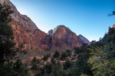 Kum tepeleri, Utah 'ta gün batımının ılık ışığını yakalıyor. Yürüyüşçüleri, Zion Ulusal Parkı' nın manzaralı manzaralarını keşfetmeye davet ediyor..