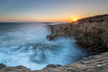 Güneş batarken dalgalar engebeli uçurumlara çarpar ve California, Malibu 'daki Leo Carrillo Eyalet Sahili' nde nefes kesici bir manzara yaratır..