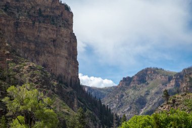 Glenwood Springs showcases dramatic cliffs and lush green valleys beneath a bright sky, highlighting the area's natural beauty and rugged landscape. clipart