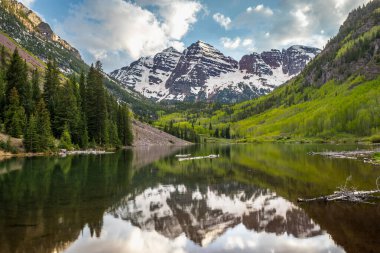 Görkemli Maroon Çanları, yemyeşil yemyeşil ve mavi gökyüzünün altında karla kaplı tepelerle çevrili sakin Maroon Gölü 'nün üzerinde yükseliyor..