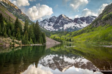 Sakin bir göl, Aspen, Colorado 'daki görkemli dağları ve ağaçları parçalı bulutlu bir gökyüzünün altında yansıtır. Doğa aşıkları için mükemmel..