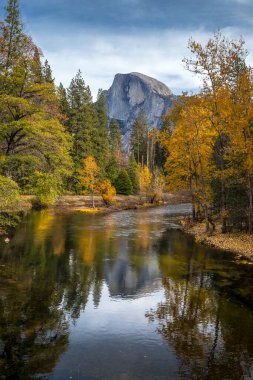 Sonbaharda Yosemite Ulusal Parkı 'na giderek Half Dome' un renkli yeşillikler ve sakin suların ortasındaki çarpıcı yansımasını görün..