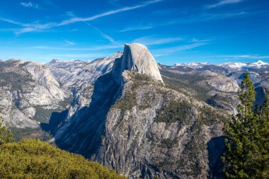 Ziyaretçiler Half Dome 'un nefes kesici manzarasını ve Buzul Noktası' ndan sakin manzaranın tadını çıkarıyorlar. Bu ikonik nokta doğanın cennetinde sakin yürüyüşler sunuyor..