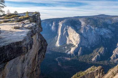 Yosemite Ulusal Parkı 'ndaki Taft Point' te yürüyüşçüler, açık gökyüzü altındaki Sierra Nevada Dağları ve sembolik Half Dome 'un nefes kesici manzarasının keyfini çıkarıyorlar..