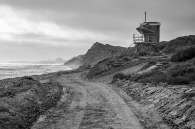 A lifeguard tower overlooks the rugged coastline of San Clemente on a cloudy day, highlighting the serene beauty of the bluffs. clipart