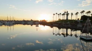 Gökkuşağı Limanı, Long Beach, California 'nın güneşli havadan çekimleri sakin sularla birlikte renkli gökyüzünü yansıtıyor.