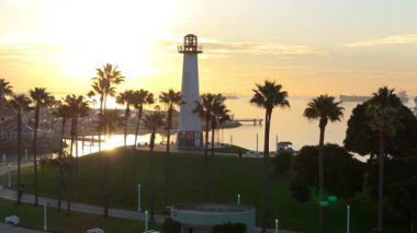 Lions Lighthouse ve Shoreline Aquatic Park 'ın gündoğumunda çekilen hava yörüngesi görüntüleri Long Beach, Kaliforniya' daki sakin suları ve uzak gemileri gösteriyor..