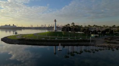 Lions Lighthouse ve Shoreline Aquatic Park 'ın gündoğumunda çekilen hava yörüngesi görüntüleri Long Beach, Kaliforniya' daki sakin suları ve uzak gemileri gösteriyor..