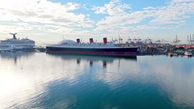 Queen Mary gemisinin şafak vakti Long Beach sahil limanında gökyüzünde bulutlarla muhteşem bir görüntüsü.