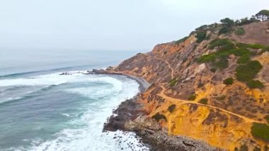 Hava yörüngesinde sörfçünün dramatik Bluff Cove Patikası 'na tırmanışının görüntüsü Float Point Rock, Palos Verdes Estates, Kaliforniya' da bulutlu bir günde