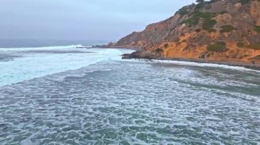 Bluff Cove, Palos Verdes Estates, Kaliforniya 'nın çarpıcı hava durumu bulutlu bir günde dalgalar engebeli kıyı şeridine çarpıyor.