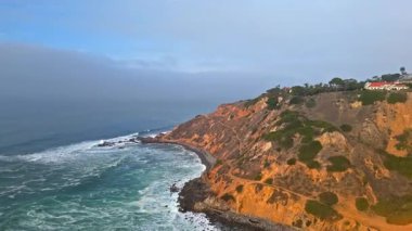 Palos Verdes Estates, Kaliforniya 'da bulutlu bir günde dalgaların yukarıdan aşağıya doğru kayalık kıyılara çarpması.