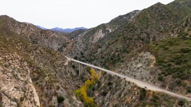 Los Angeles Ulusal Ormanı, Kaliforniya 'da Büyük Tujunga Narrows Köprüsü' nün altında uçan hava manzarası canlı sonbahar yeşillikleri ve görkemli dağ manzaraları sergiliyor..