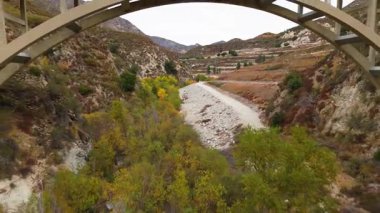 Los Angeles Ulusal Ormanı, Kaliforniya 'daki Büyük Tujunga Köprüsü' nün altında uçan hava manzarası canlı sonbahar yaprakları ve görkemli dağ manzaralarını gözler önüne seriyor..
