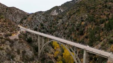 Angeles Orman Yolu boyunca uzanan Büyük Tujunga Narrows Köprüsü Havalimanı, Angeles Ulusal Ormanı, Kaliforniya, canlı sonbahar yeşillikleri ve görkemli dağ manzaraları sergilenmektedir..