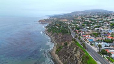 Los Angeles, Kaliforniya 'daki Point Fermin' in alçak hava manzarası, engebeli okyanus kayalıkları, çarpan dalgalar ve karamsar bulutlu kıyı manzarası