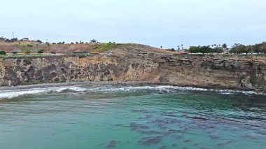 Los Angeles, Kaliforniya 'daki Point Fermin' in alçak hava manzarası, engebeli okyanus kayalıkları, çarpan dalgalar ve karamsar bulutlu kıyı manzarası