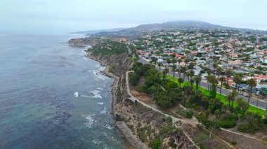 Los Angeles, Kaliforniya 'daki Point Fermin' in alçak hava manzarası, engebeli okyanus kayalıkları, çarpan dalgalar ve karamsar bulutlu kıyı manzarası