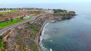 Los Angeles, Kaliforniya 'daki Point Fermin' in alçak hava manzarası, engebeli okyanus kayalıkları, çarpan dalgalar ve karamsar bulutlu kıyı manzarası
