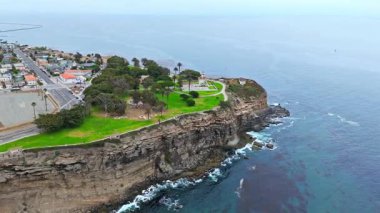 Los Angeles, Kaliforniya 'daki Point Fermin' in alçak hava manzarası, engebeli okyanus kayalıkları, çarpan dalgalar ve karamsar bulutlu kıyı manzarası