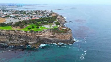 Los Angeles, Kaliforniya 'daki Point Fermin' in alçak hava manzarası, engebeli okyanus kayalıkları, çarpan dalgalar ve karamsar bulutlu kıyı manzarası
