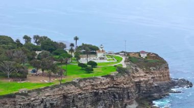 Los Angeles, Kaliforniya 'daki Point Fermin' in alçak hava manzarası, engebeli okyanus kayalıkları, çarpan dalgalar ve karamsar bulutlu kıyı manzarası