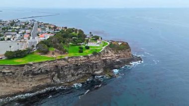 Los Angeles, Kaliforniya 'daki Point Fermin' in alçak hava manzarası, engebeli okyanus kayalıkları, çarpan dalgalar ve karamsar bulutlu kıyı manzarası