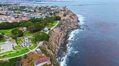 Los Angeles, Kaliforniya 'daki Point Fermin' in alçak hava manzarası, engebeli okyanus kayalıkları, çarpan dalgalar ve karamsar bulutlu kıyı manzarası