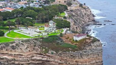 Los Angeles, Kaliforniya 'daki Point Fermin' in alçak hava manzarası, engebeli okyanus kayalıkları, çarpan dalgalar ve karamsar bulutlu kıyı manzarası