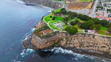 Los Angeles, Kaliforniya 'daki Point Fermin' in alçak hava manzarası, engebeli okyanus kayalıkları, çarpan dalgalar ve karamsar bulutlu kıyı manzarası