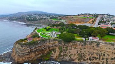 Los Angeles, Kaliforniya 'daki Point Fermin' in alçak hava manzarası, engebeli okyanus kayalıkları, çarpan dalgalar ve karamsar bulutlu kıyı manzarası
